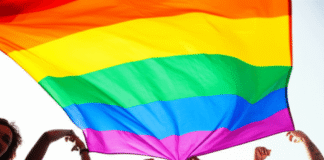 LGBTQ+ Equality: Key Milestones and Challenges Ahead Diverse Group Forms Heart Under Rainbow Flag