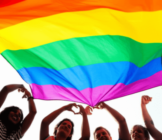 LGBTQ+ Equality: Key Milestones and Challenges Ahead Diverse Group Forms Heart Under Rainbow Flag