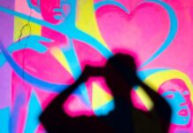 5 LGBTQ+ Art Exhibitions You Can’t Miss in 2025 Oversaturated queer mural with huge foreground shadow.